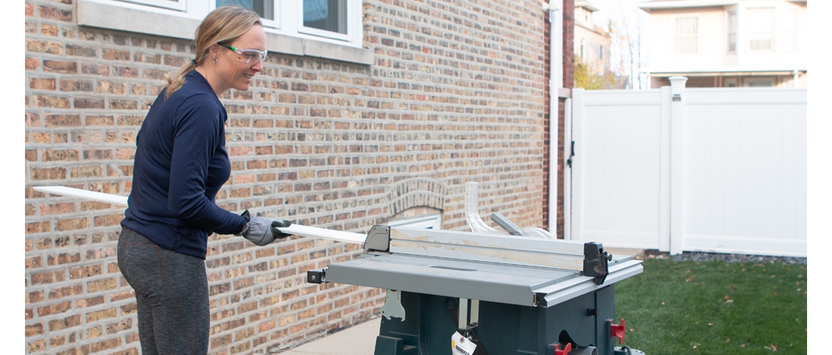 Person outside wearing safety glasses, using a table saw.