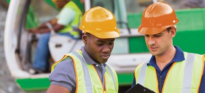 Two workers standing outside at a jobsite.
