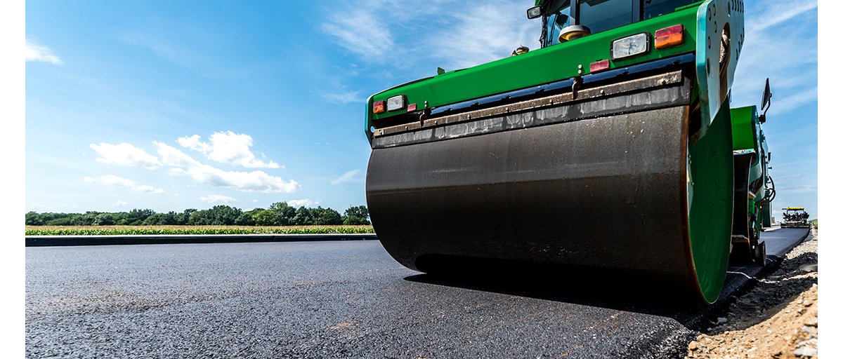 A close-up photo of a double drum roller compacting asphalt.