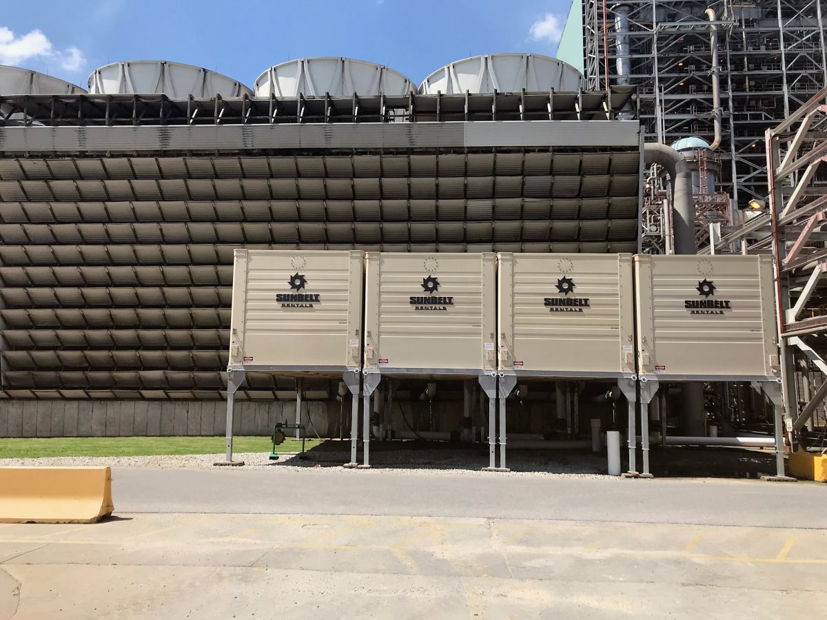 Four Sunbelt Rentals cooling towers side-by-side on a cement pad outside an industrial facility.