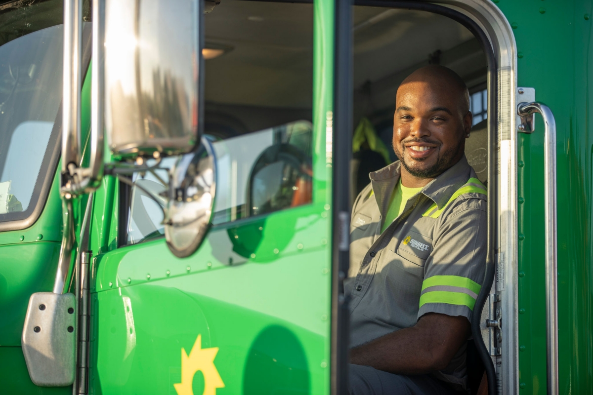 A Sunbelt Rentals employee sitting in a green delivery truck. 