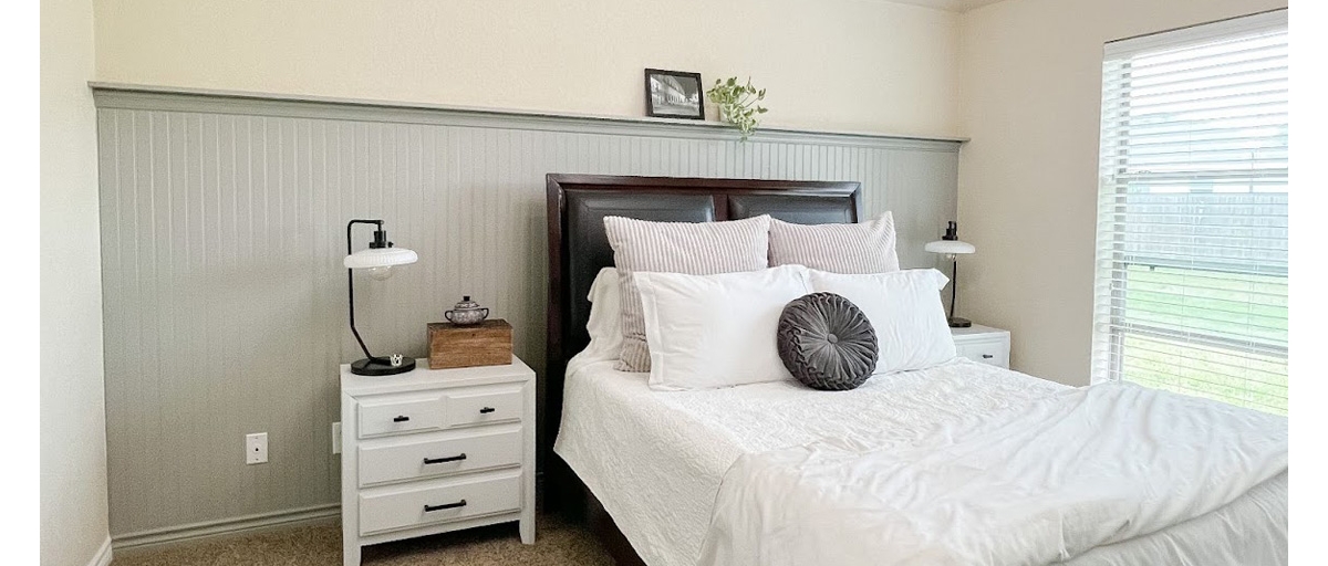 Bedroom with a neutral, beadboard accent wall.