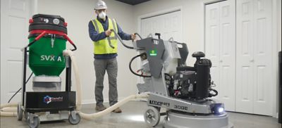 Someone wearing safety apparel using a concrete grinder.