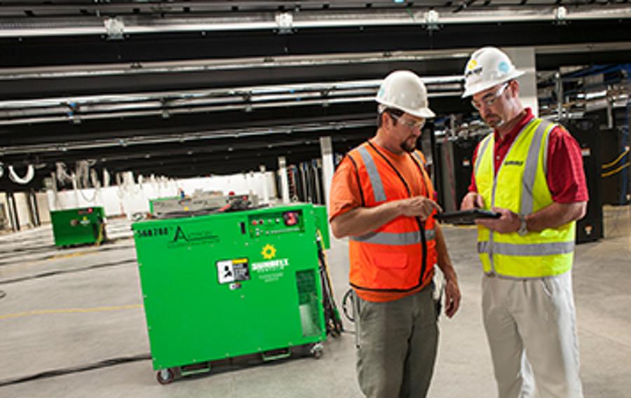 Two people standing in front of a generator.