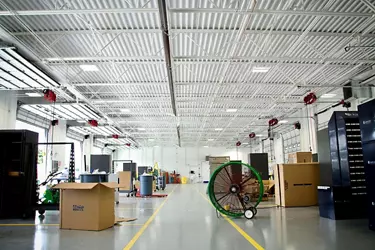 A large round fan running in the middle of a warehouse.