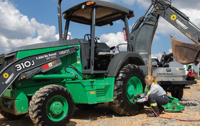 A person working on a backhoe's tire.