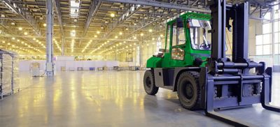 Forklift on concrete floor inside of a warehouse.