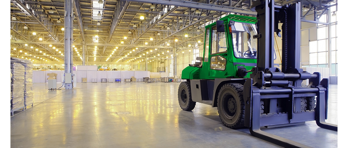 A green forklift parked inside a warehouse.