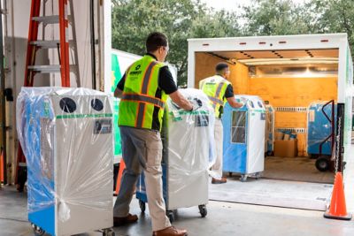 People wearing safety apparel load climate control equipment onto a truck.