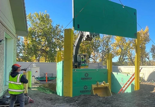 People wearing safety equipment installing a slide rail panel on a shoring system.