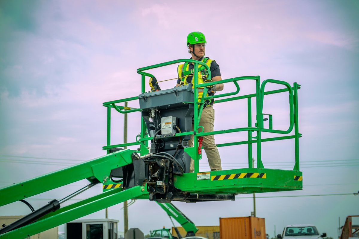 A person wearing safety apparel using an aerial work platform.