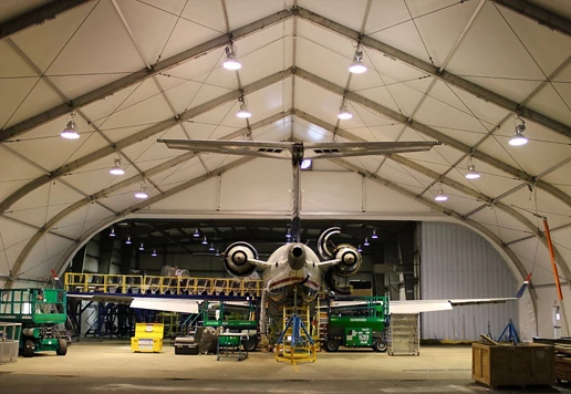 Airplane in a hangar surrounded by green Sunbelt Rentals equipment. 