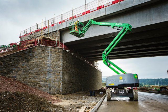 Sunbelt Rentals telehandler supporting a worker fixing a bridge. 
