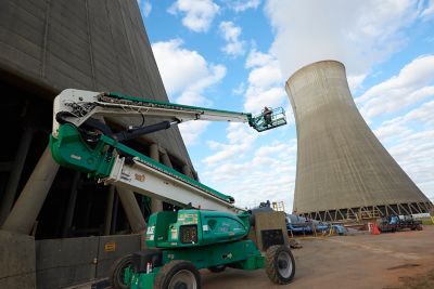 Someone operating an articulating manlift near nuclear cooling towers.