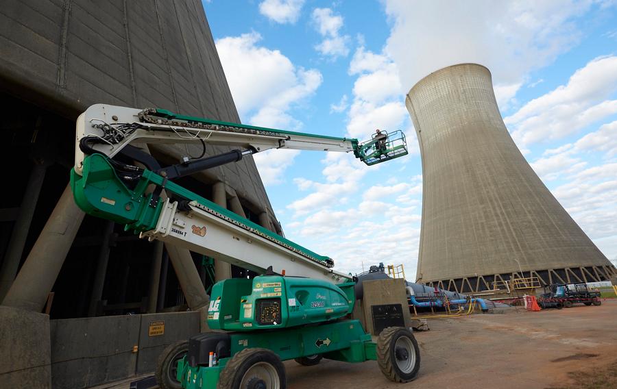 Someone operating an articulating manlift near nuclear cooling towers.