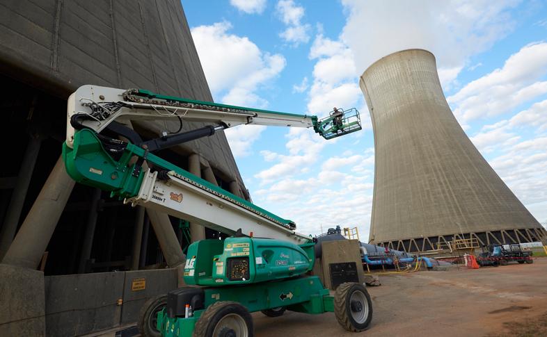 Someone operating an articulating manlift near nuclear cooling towers.