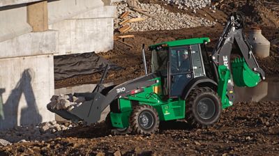 A backhoe loader picking up rocks at a construction site.