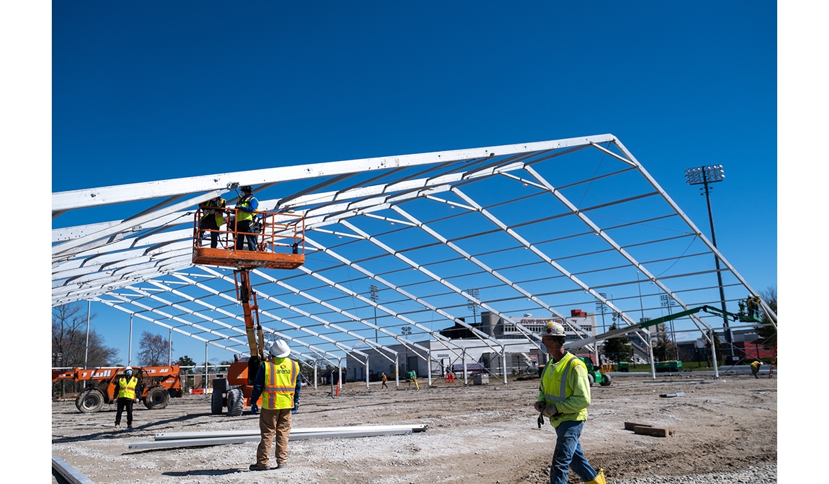 People wearing safety apparel installing the framework of a temporary structure.