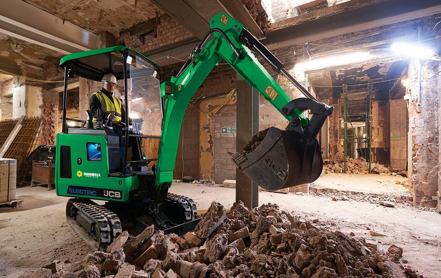 Someone driving a mini excavator inside of a building under construction.