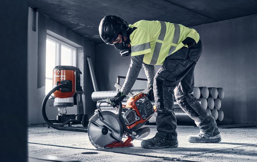 Someone wearing safety apparel operating battery-powered saw.