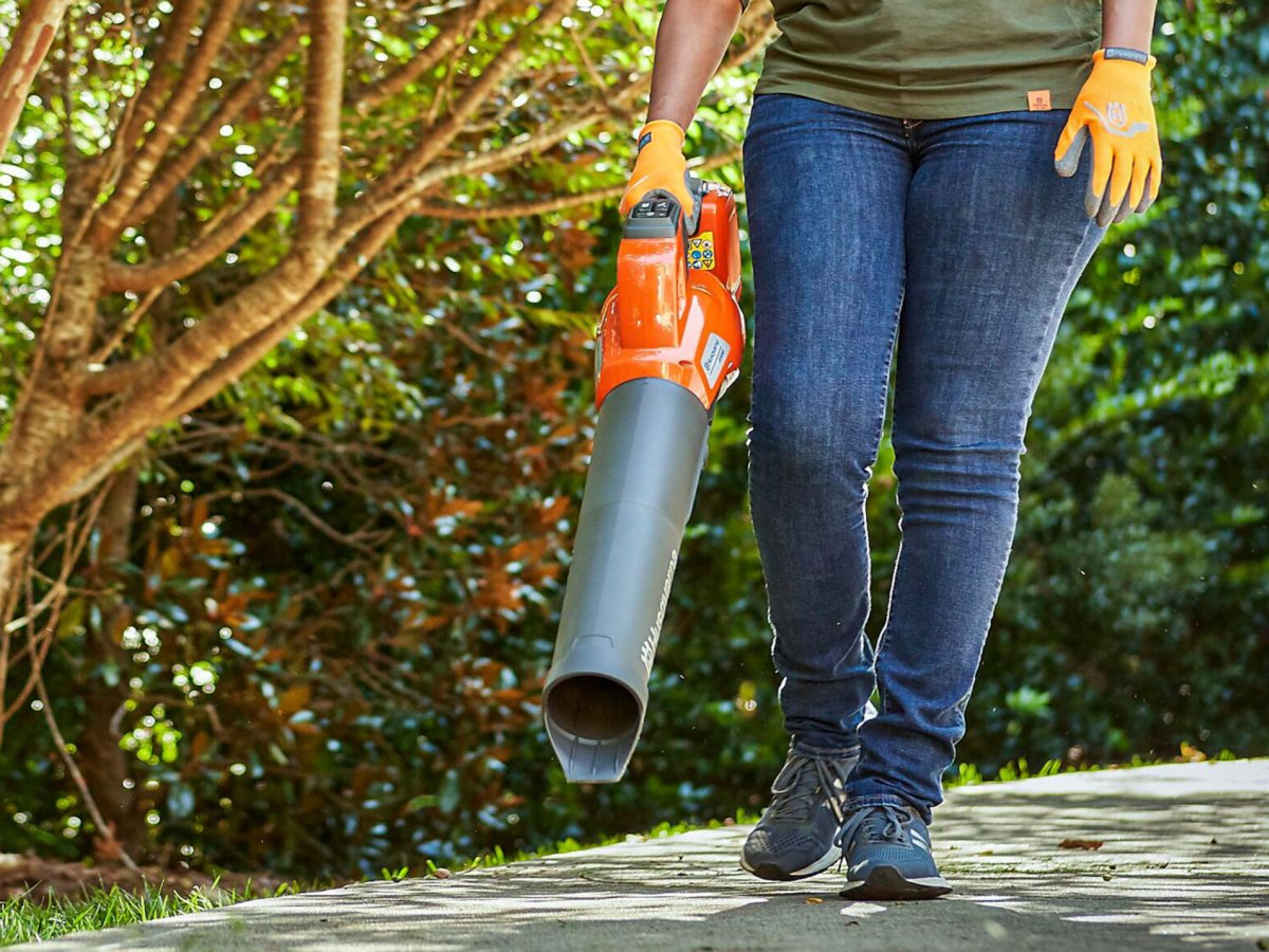 A handheld blower used on a sidewalk.