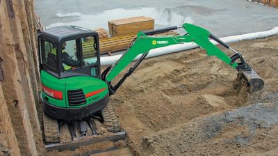 A mini exvacator from Sunbelt Rentals moving dirt at a job site.
