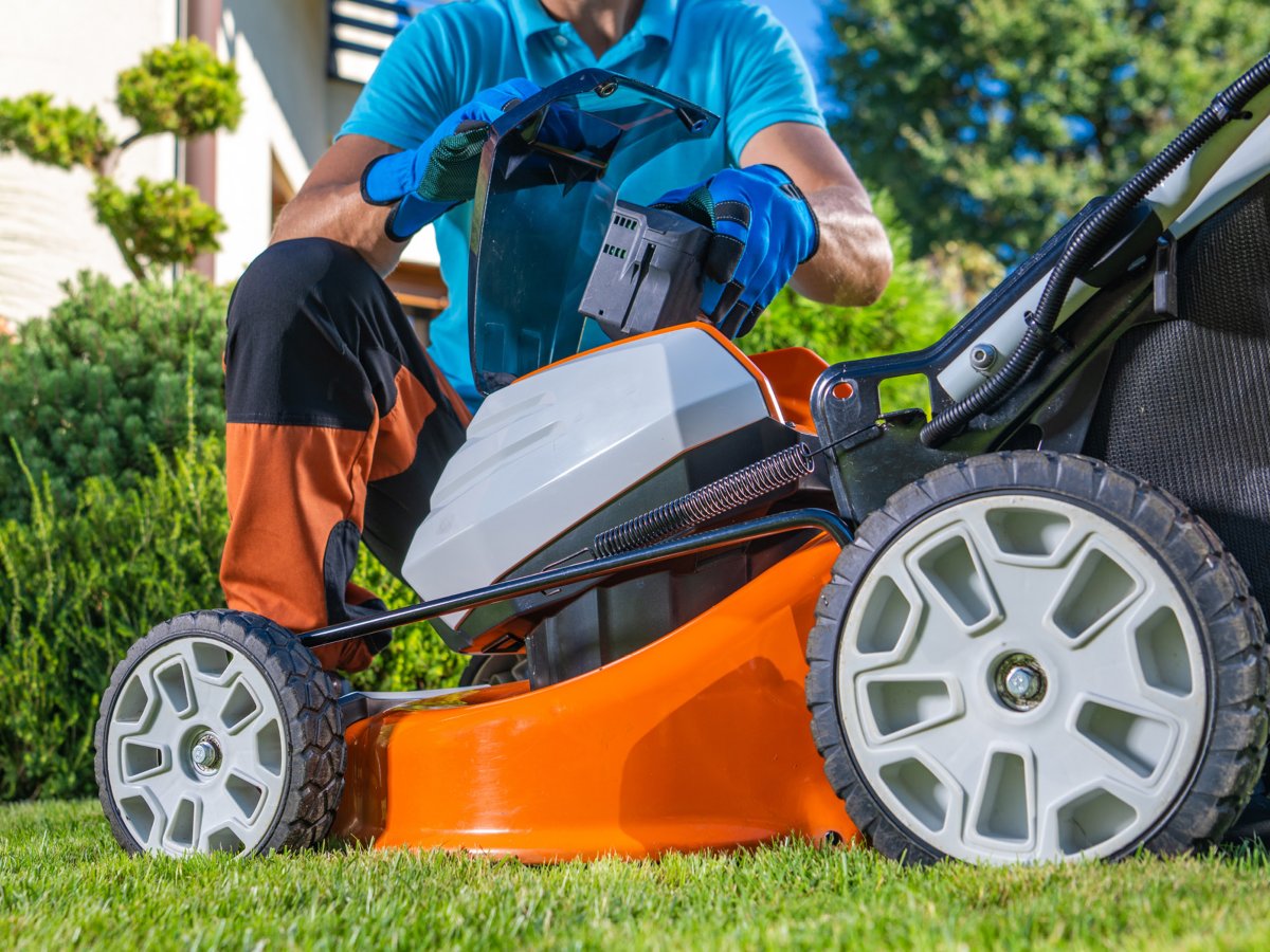 A battery mower with the battery cover open.