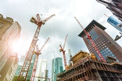 Multiple cranes at a construction site in a city.