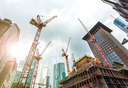 Multiple cranes at a construction site in a city.