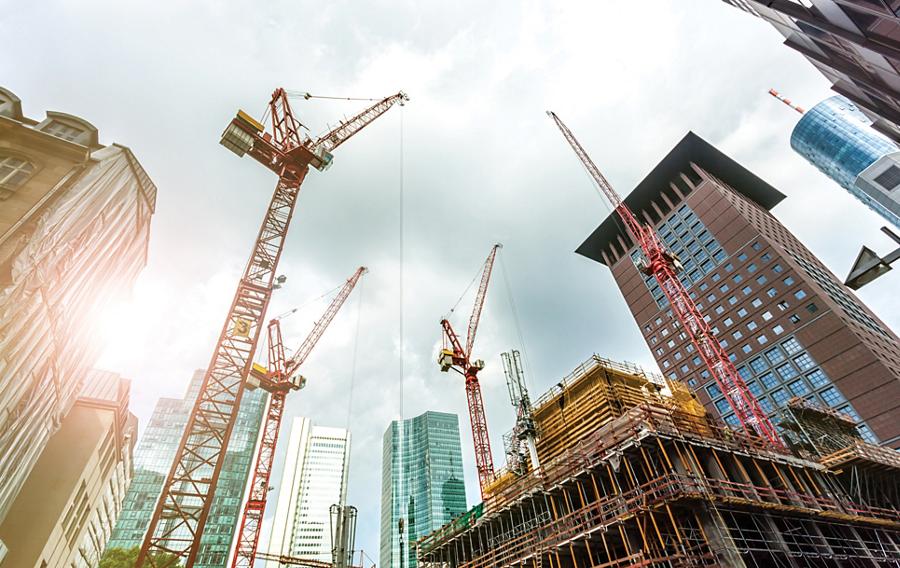 Multiple cranes at a construction site in a city.