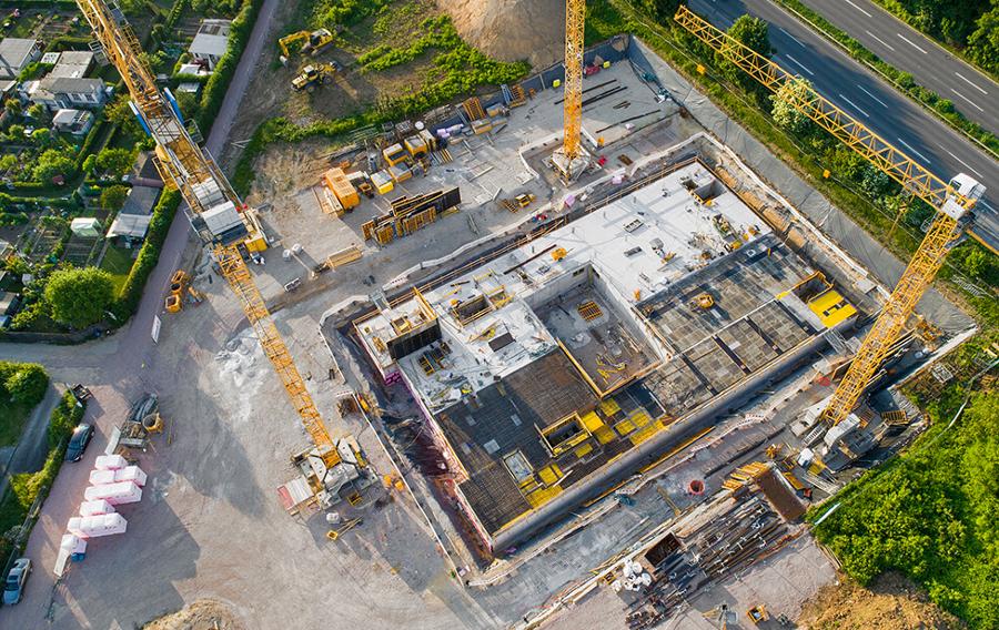A construction site with yellow cranes around a building foundation.