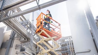Someone using an all-electric scissor lift at a job site.