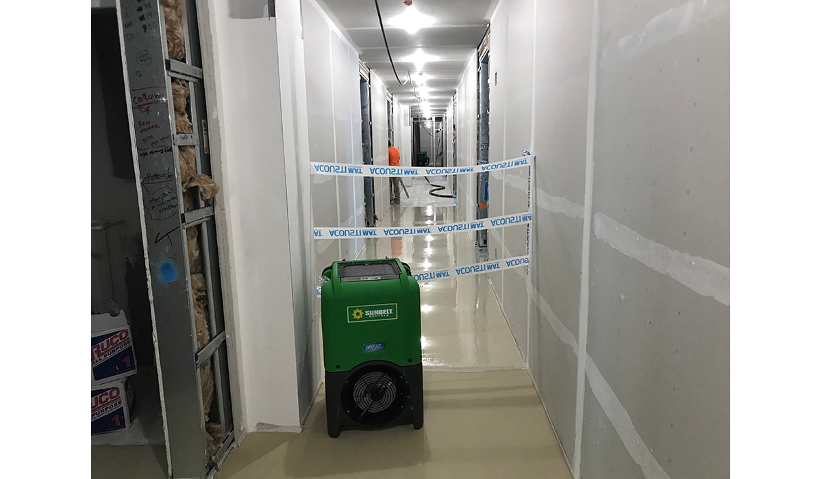 A dehumidifier from Sunbelt Rentals in the hallway of a building under construction.