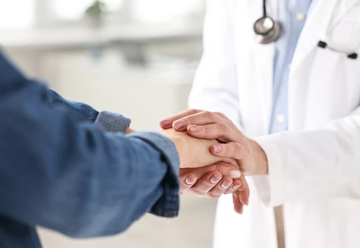 A close-up view of a medical professional holding a patient's hand.