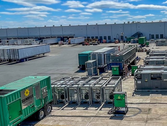 Chillers and generators outside of a large industrial building.