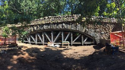 An engineered protective system supports the underside of a stone bridge.