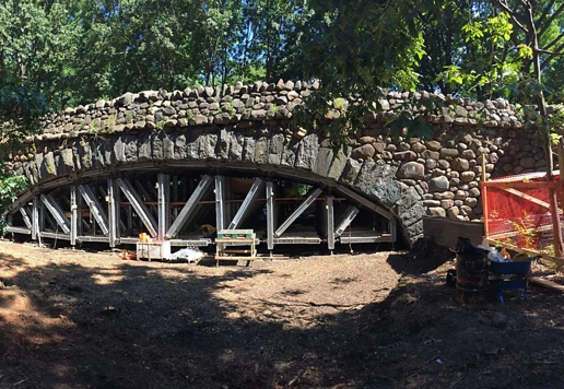An engineered protective system supports the underside of a stone bridge.