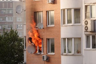 Fire coming outside of the window from a residential building.