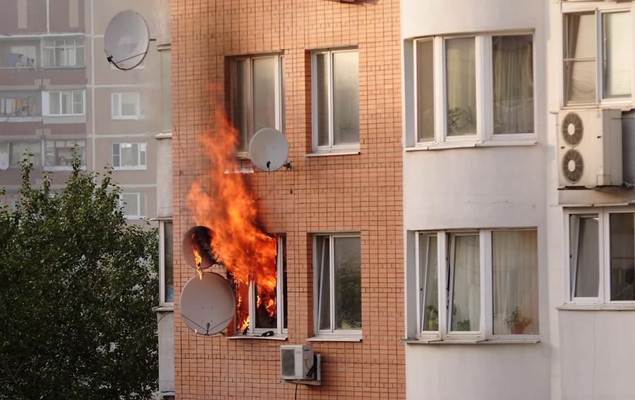 Fire coming outside of the window from a residential building.