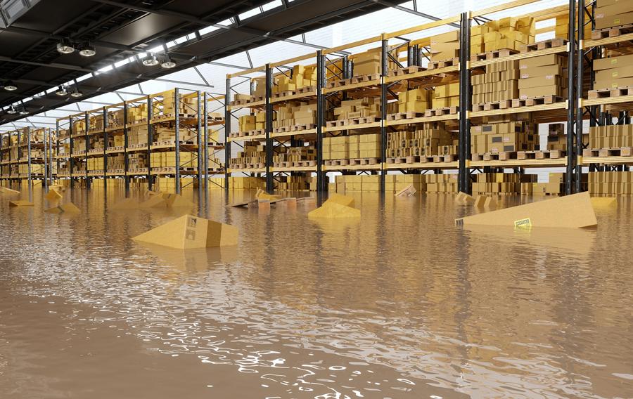 A flooded warehouse with cardboard boxes floating on water.