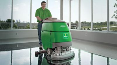 Someone operating a floor scrubber in a large, open building.
