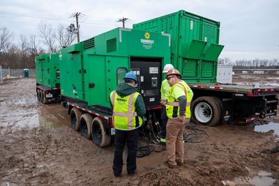 People checking generators outside at a job site.