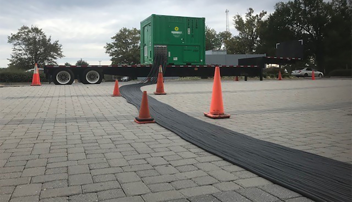 A generator from Sunbelt Rentals installed in a parking lot marked with safety cones.