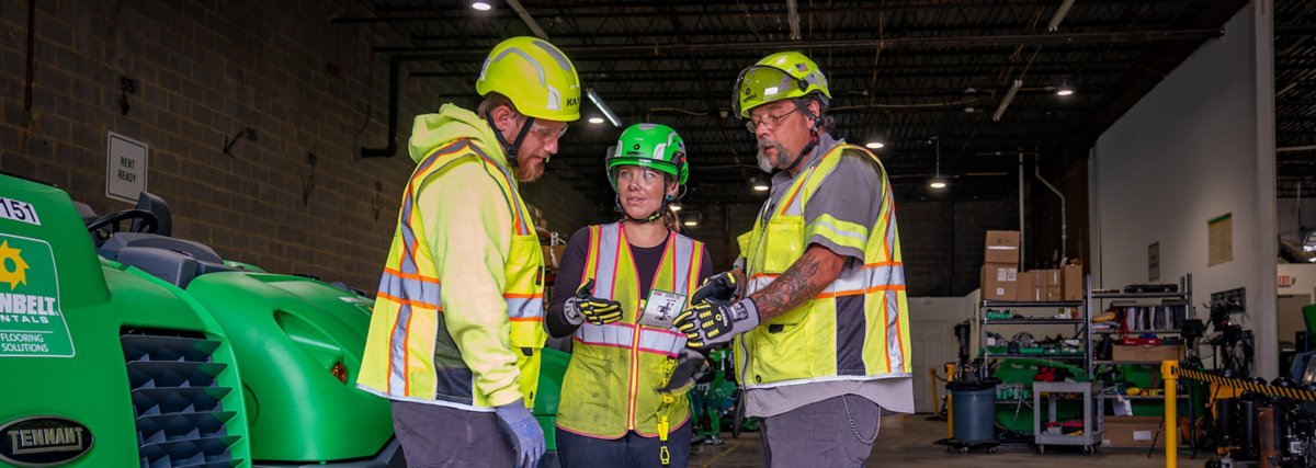A group of three people wearing safety apparel conversing.