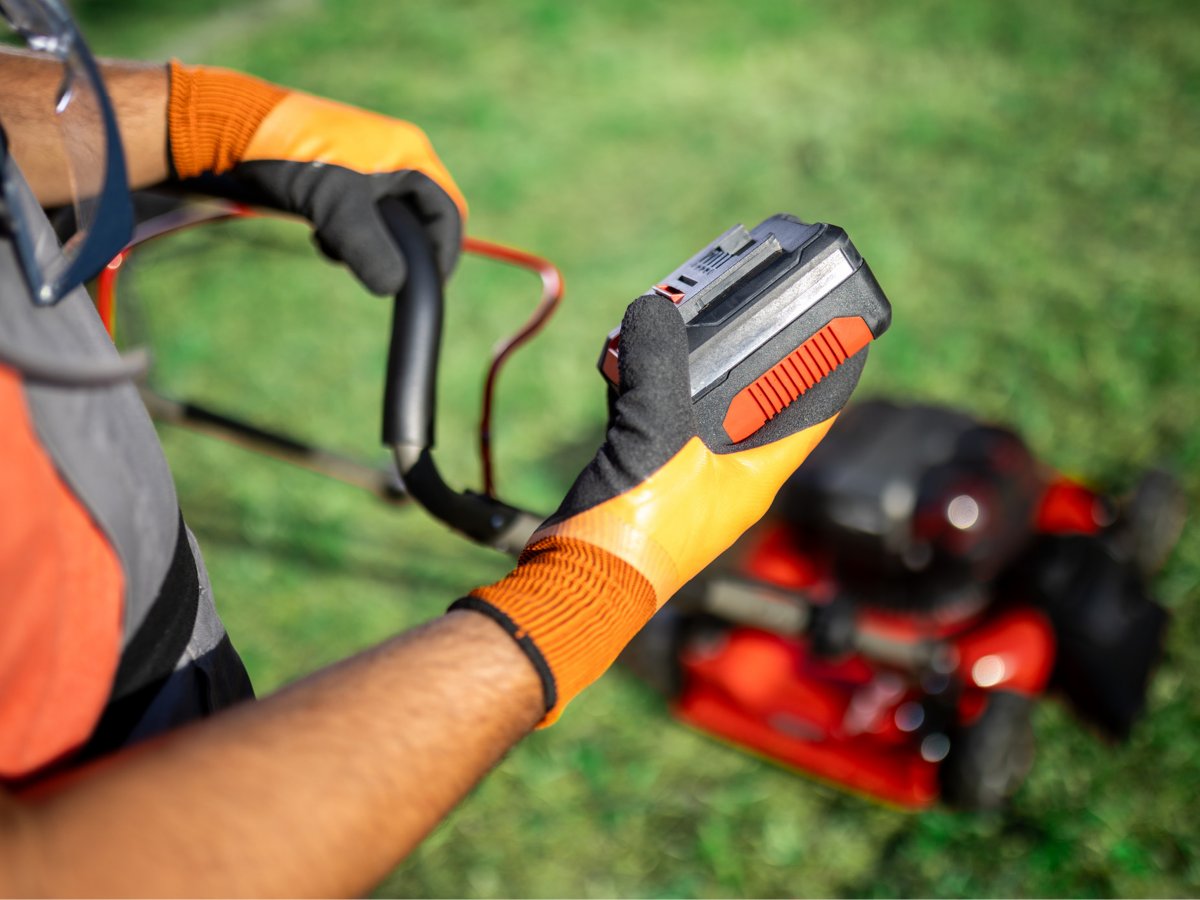 Someone holding a battery pack from a battery mower.