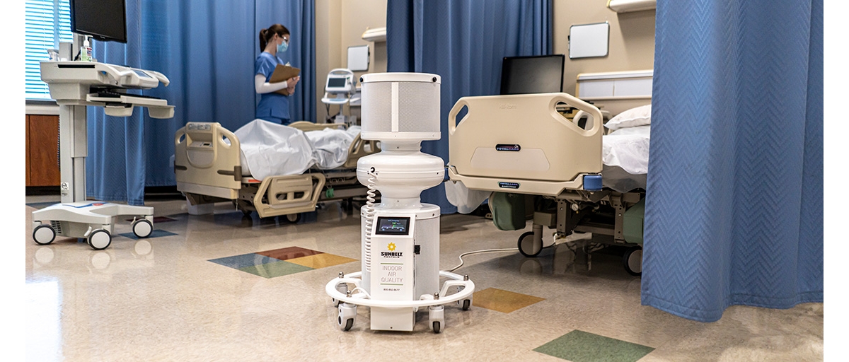 An air scrubber sitting in front of two hospital beds.