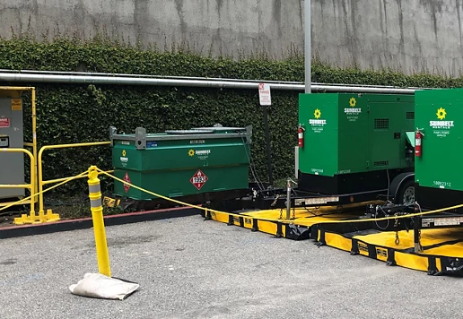 Green painted portable generators from Sunbelt Rentals sitting on yellow and black containment berms.