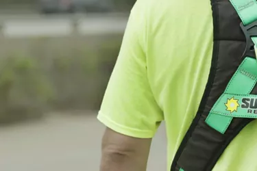 Technician in green shirt with Sunbelt Rentals safety harness