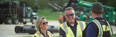 People wearing safety apparel stand in front of Sunbelt Rentals equipment.