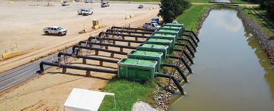 A row of pumps from Sunbelt Rentals at a jobsite's small body of water.